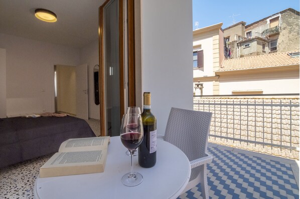 A balcony with a table, a chair, a wine bottle, and a book.