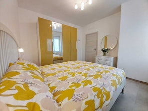 Une chambre à coucher comprenant un lit, une armoire, une commode, un miroir et un luminaire fixé au plafond.