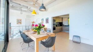 A modern dining area with a wooden table, black wireframe chairs, and a vase of flowers.