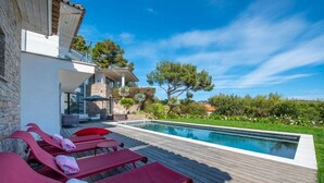 A modern outdoor pool area with lounge chairs and a stone building.