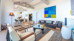 A modern living room with a sofa, armchairs, a coffee table, and a colorful abstract painting.