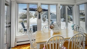 A sunroom with a wooden table and white chairs, large windows, and a decorative swan.