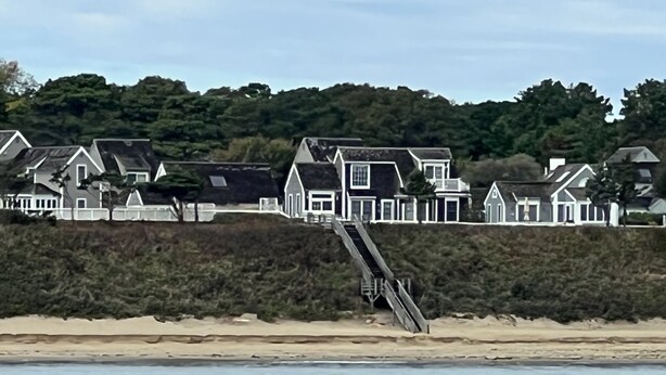 A coastal residential area with houses built on a hillside overlooking the beach.