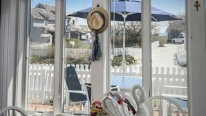 A room with a view of a white picket fence, a dining table with a swan-shaped centerpiece, and a hat hanging on the wall.