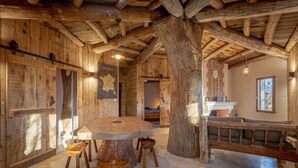 A rustic wooden interior with a large round table, wooden chairs, and a bench. - Le Cul de Loup, self-catering cottage (Crouy-sur-Cosson)
