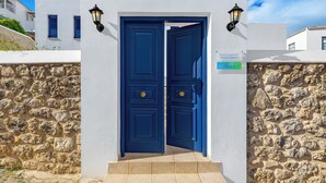 Un bâtiment blanc avec une porte bleue et deux lampes noires fixées au mur.