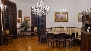 Ein Essbereich mit einem runden Tisch und Stühlen, einer Deckenleuchte, einem Weihnachtsbaum und gerahmten Kunstwerken an den Wänden.