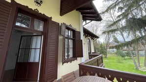 Ein hölzerner Balkon mit Blick auf eine grüne Wiese und Bäume.