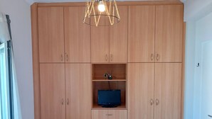 A large wooden wardrobe with multiple drawers and a television on a shelf. - Cozy Studio at Kallithea, Fully Equipped (Nea Smirni)