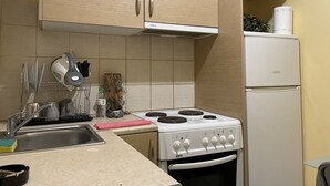A kitchen with beige cabinets, a white stove, and a white refrigerator. - Cozy Studio at Kallithea, Fully Equipped (Nea Smirni)