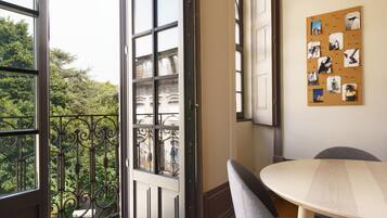 Een kamer met balkon, prikbord met foto's en een ronde tafel.