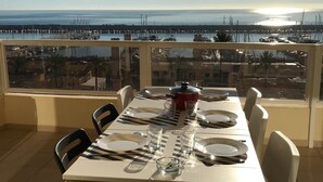 A dining table set on a balcony with a view of a marina and boats.