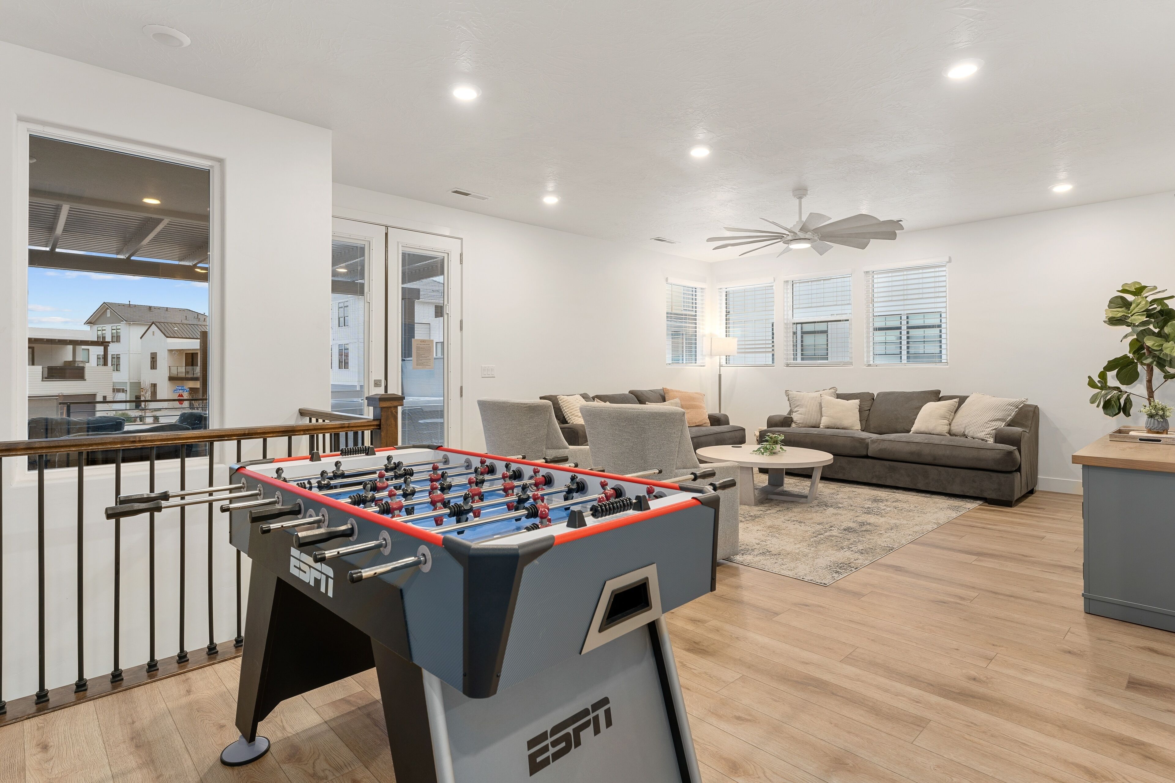 A modern living room with a foosball table, a sofa set, and a dining area.