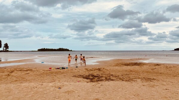 Una playa con arena, algunas personas y un cielo nublado.