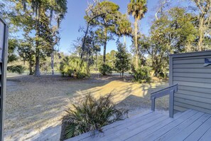 Une terrasse en bois dotée d’une rambarde, entourée de différents types d’arbres et d’arbustes.