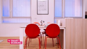 Una cucina moderna con un piano di lavoro bianco, due sedie rosse e una citazione ispiratrice incorniciata al muro.