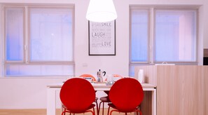 Une cuisine moderne avec un plan de travail blanc, deux chaises rouges et un cadre affichant une citation inspirante au mur.