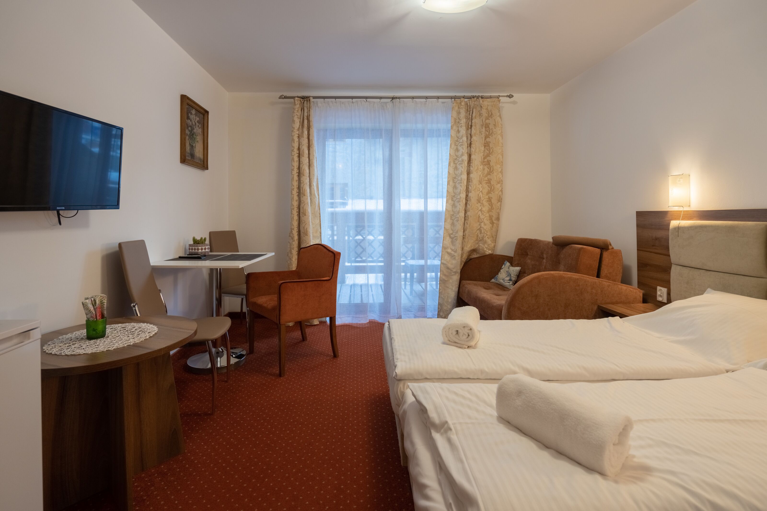 Une chambre d’hôtel avec un lit, un bureau, une chaise, une télévision et un balcon donnant sur une vue agréable.
