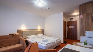 A hotel room with two single beds, a sofa, a chair, a small table, and a microwave. - RentPlanet - Apartamenty Okrzei (Szklarska Poreba)