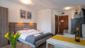 A hotel room with a bed, bedside lamps, a table with a bottle of wine, and a wall-mounted TV. - RentPlanet - Apartamenty Okrzei (Szklarska Poreba)