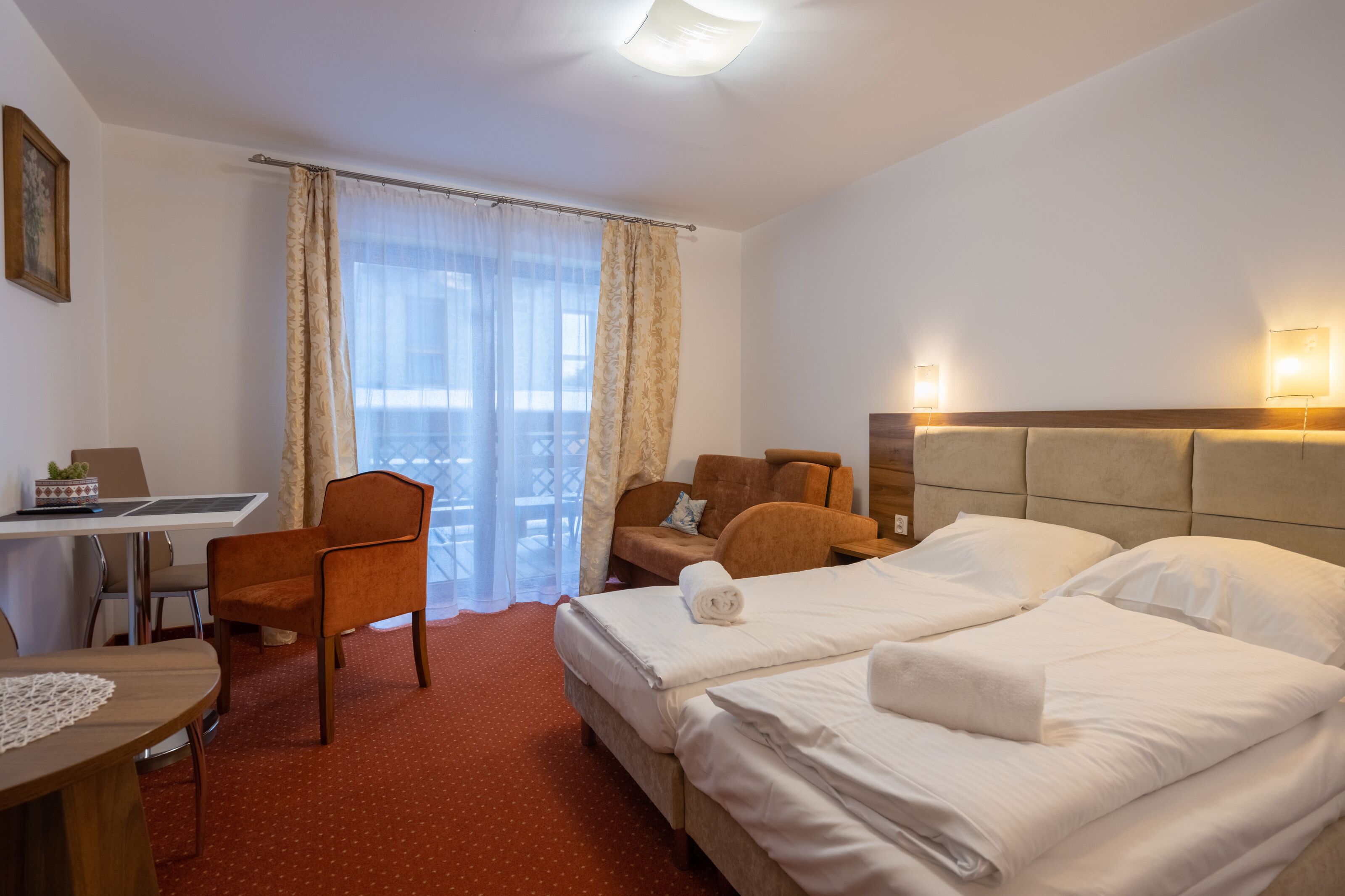 Ein Hotelzimmer mit zwei Betten, einem Schreibtisch, einem Stuhl und Blick ins Freie.