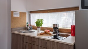 A kitchen with a wooden countertop, a sink, a coffee maker, a toaster, and a window with a plant. - RentPlanet - Apartamenty Okrzei (Szklarska Poreba)