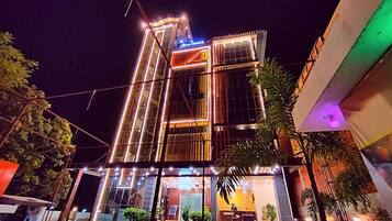 A multi-story building with a modern architectural design, featuring a prominent glass facade and illuminated signage.