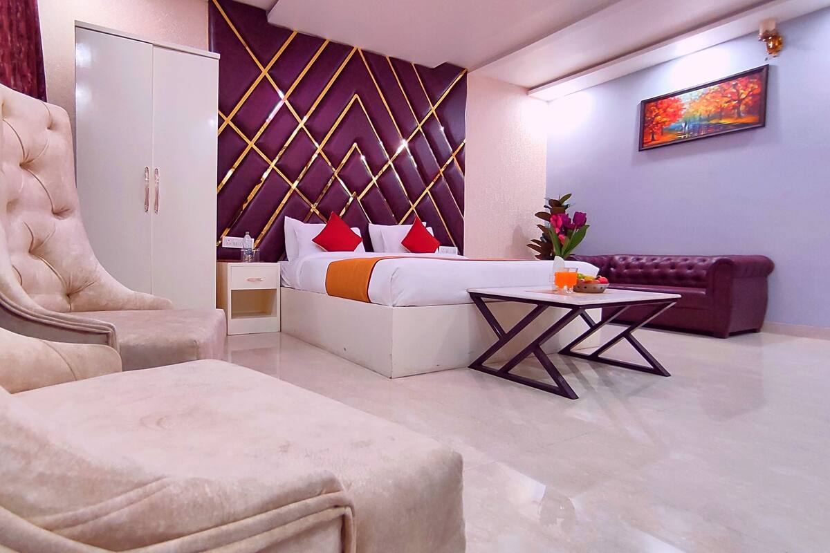 Ein modernes Hotelzimmer mit einem großen Bett, einer Couch, einem Sessel und einem kleinen Tisch.