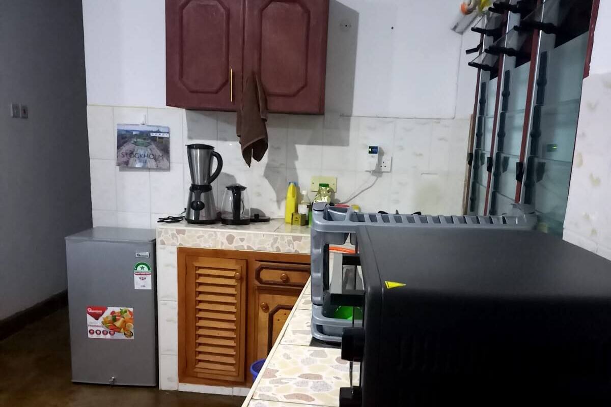 Eine kleine Küche mit Kühlschrank, Kaffeemaschine und Spüle.