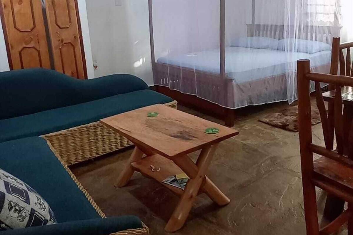 Ein Zimmer mit einem Bett unter einem Moskitonetz, einer Couch, einem Holztisch und einem Stuhl.