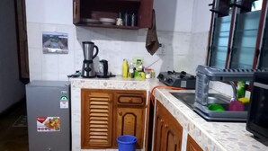 A compact kitchen with wooden cabinets, a small refrigerator, and a sink. - Stay. Plus Darad Homes Diani (Ukunda)