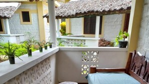A small balcony with a wooden bench, a round table, and potted plants. - Stay. Plus Darad Homes Diani (Ukunda)