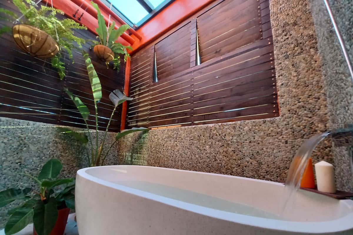 Ein Wellnessbereich mit Badewanne, Topfpflanzen und einer Steinwand.