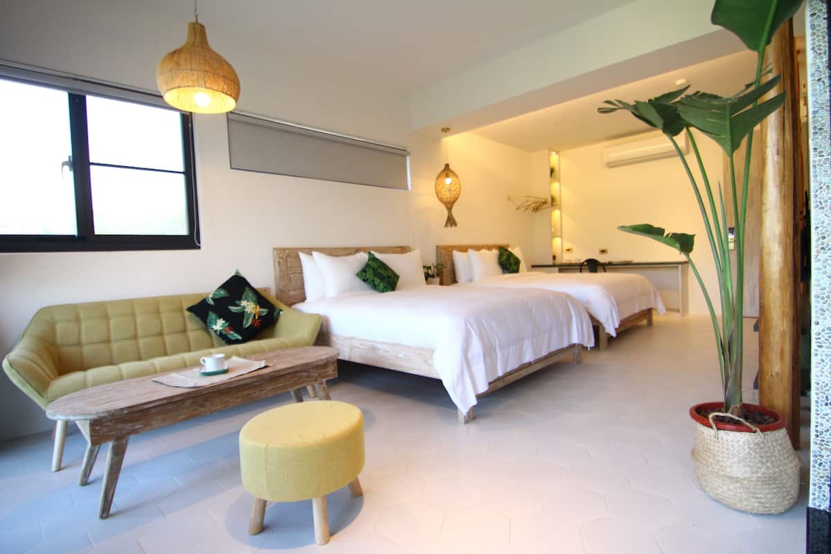 Ein Schlafzimmer mit einem Bett, einer Couch, einem Holztisch und einer Topfpflanze.