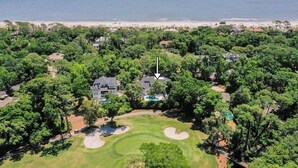 An aerial view of a golf course with a house, a swimming pool, and a beach in the background. - 49 Mooring Buoy - Luxury Private Home, Golf Views (Hilton Head Island)