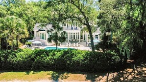 A large house with a swimming pool, surrounded by lush greenery and trees. - 49 Mooring Buoy - Luxury Private Home, Golf Views (Hilton Head Island)