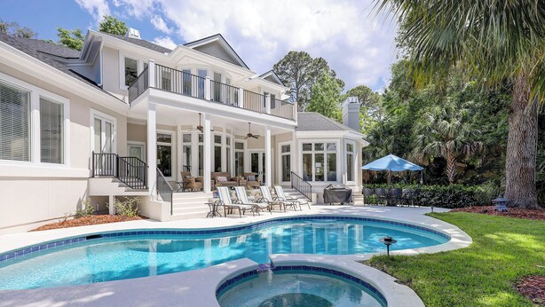 A modern two-story house with a large swimming pool, outdoor seating, and a covered patio area. - 49 Mooring Buoy - Luxury Private Home, Golf Views (Hilton Head Island)