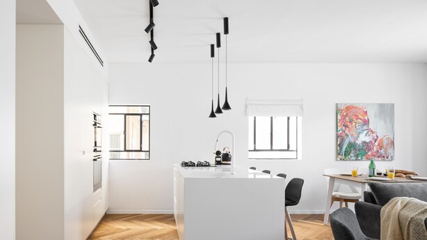 A modern kitchen with a central island, pendant lights, and a dining area with a table and chairs. - A Modern and Homely 2BD Apartment in TLV (Tel Aviv)