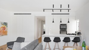 A modern kitchen with a central island, bar stools, and a dining table. - A Modern and Homely 2BD Apartment in TLV (Tel Aviv)