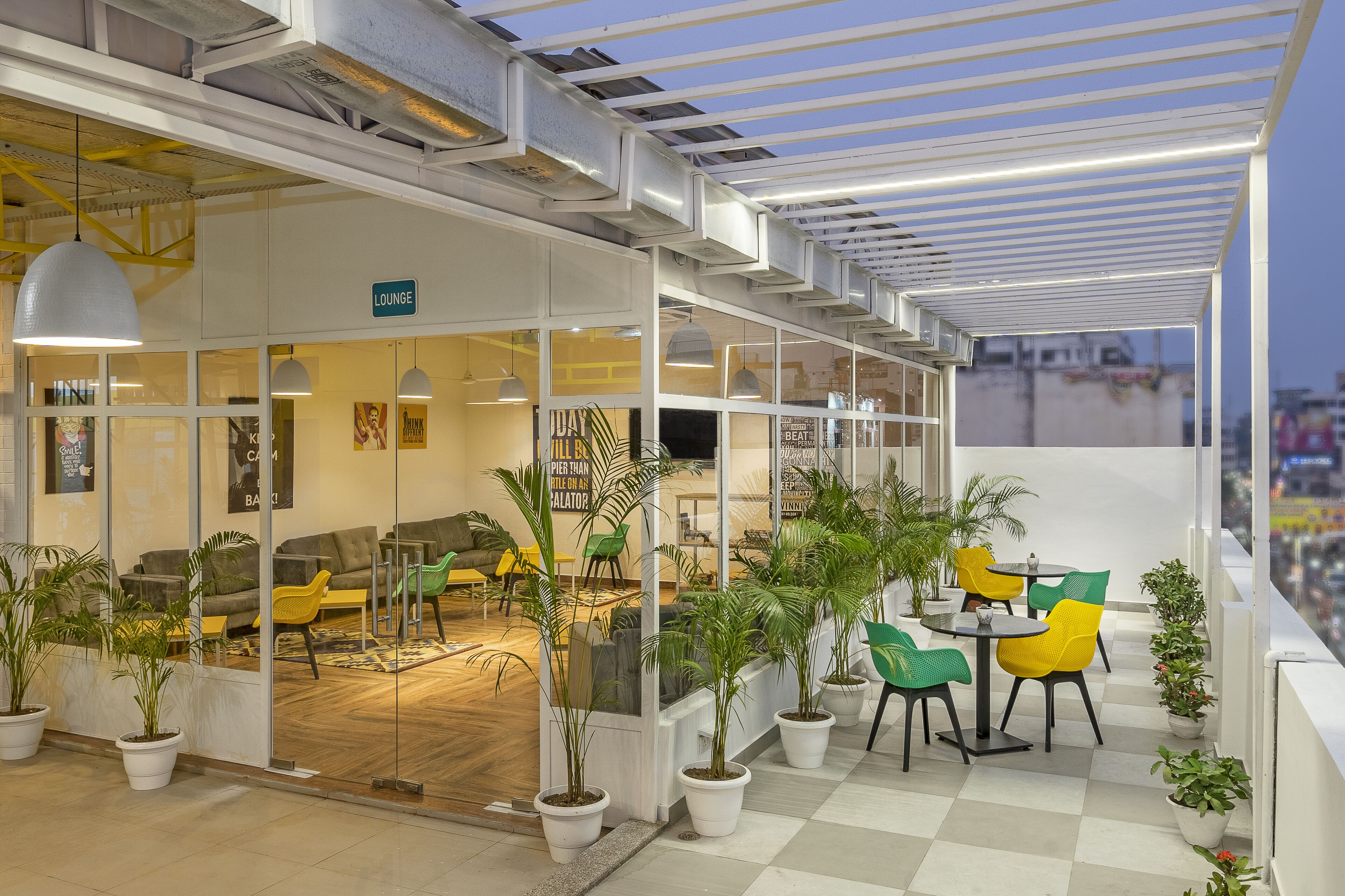 Un área de descanso con asientos y plantas en macetas, un suelo a cuadros y vistas a la ciudad.