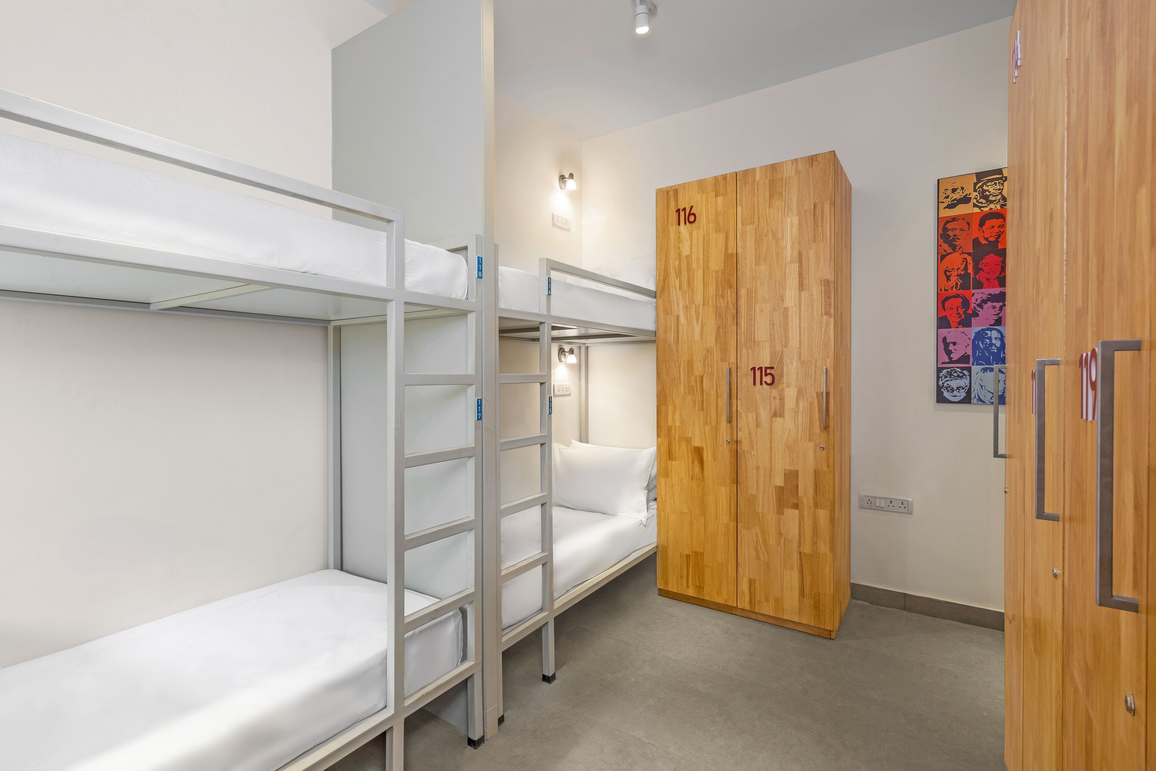 Un dormitorio con literas, un armario de madera y una lámpara fijada a la pared.