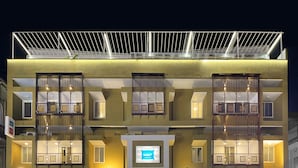 A multi-story hotel with balconies, large windows, and solar panels on the roof. - Bedzzz Varanasi by Leisure Hotels (Varanasi)
