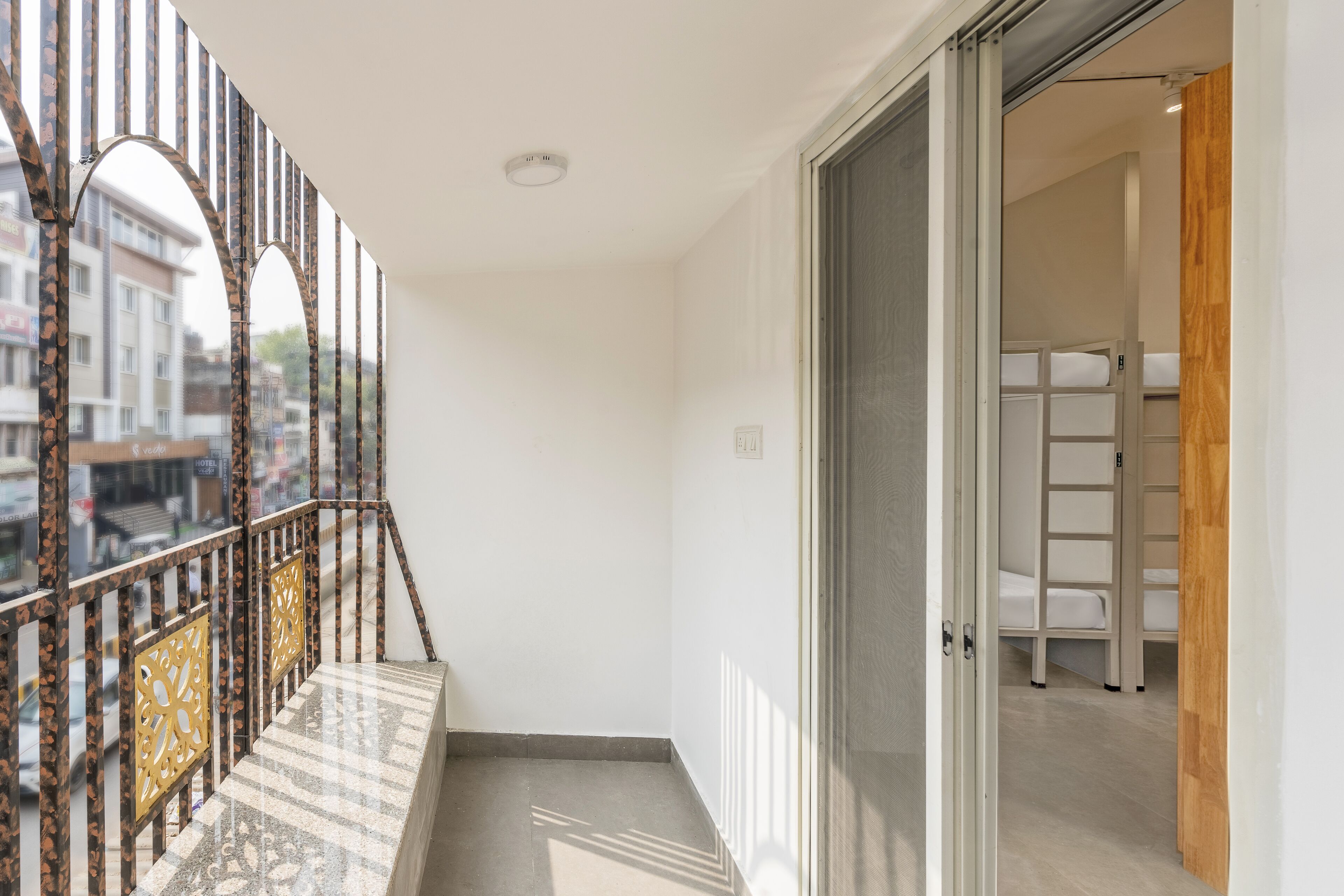 Un balcone stretto con ringhiera metallica e vista sugli edifici circostanti.