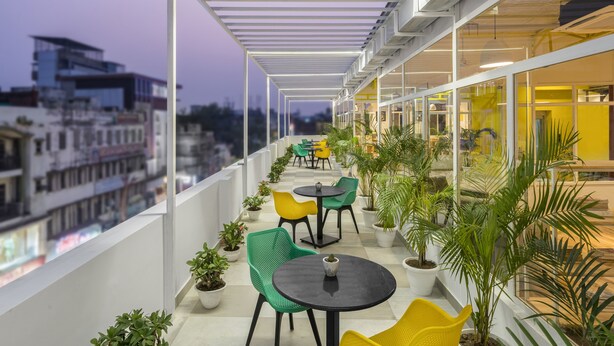 A balcony with potted plants, outdoor seating, and a view of the cityscape. - Bedzzz Varanasi by Leisure Hotels (Varanasi)