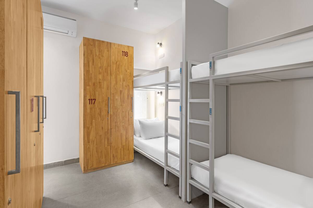 A room with bunk beds, a wooden wardrobe, and an air conditioning unit.