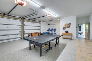 A spacious room with a ping pong table, a foosball table, and a wall-mounted rack of blue storage bins.