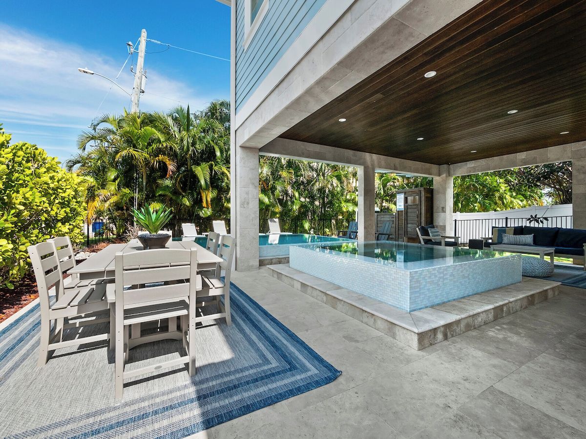 Un espace piscine extérieur avec une table et des chaises, entouré d’une végétation luxuriante.
