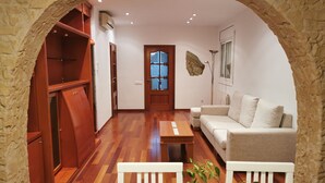 A living room with a wooden floor, a sofa, a coffee table, and an arched doorway leading to another room. - House with private pool, close to the beach and Barcelona (pet friendly) (Cunit)