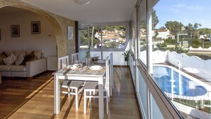 A spacious living area with a dining table set for four, a sofa, and a view of a swimming pool. - House with private pool, close to the beach and Barcelona (pet friendly) (Cunit)