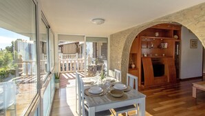 A dining area with a table set for four, a wooden bookshelf, and a stone archway leading to a balcony. - House with private pool, close to the beach and Barcelona (pet friendly) (Cunit)